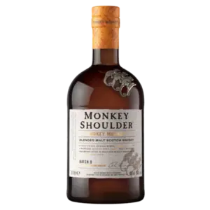 בקבוק וויסקי סקוטי מאלט בתערובת Monkey Shoulder עם כובע שזוף, הדגשות קופי מתכת על הצוואר ותווית שמנת עם טקסט שחור וזהב.